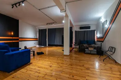 a living room with a blue couch and a wooden floor at Athena's Forge in Athens