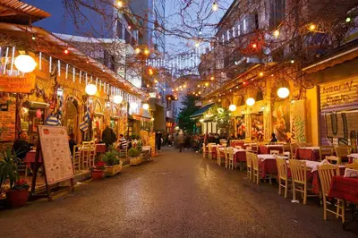 a street with tables and chairs in a city at night at Niki Athens Suites - Deluxe Suite at Historical Centre Monastiraki in Athens