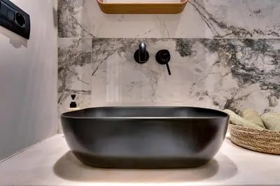 a black tub in a bathroom with a marble wall at Athens Marble - Intimate studio in Athens