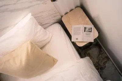 a bed with white sheets and a book on it at Athens Marble - Intimate studio in Athens