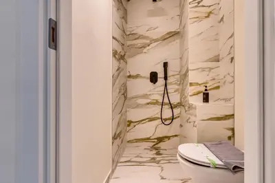 a bathroom with a toilet and marble walls at Athens Marble - Intimate studio in Athens