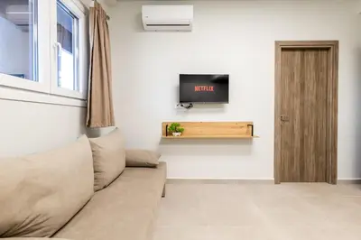 a living room with a couch and a tv on a wall at Zeus 2bd 2' minutes walk from Larissa's station in Athens
