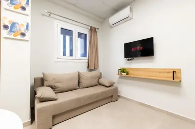 a living room with a couch and a tv at Zeus 2bd 2' minutes walk from Larissa's station in Athens