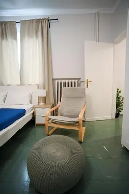 a bedroom with a chair and a bed and a rug at Athenian Suite Klathmonos by Zeus Suites in Athens