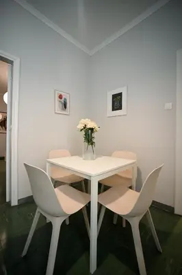 a white table with white chairs and a vase of flowers at Athenian Suite Klathmonos by Zeus Suites in Athens