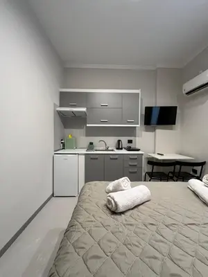 a white room with a bed and a kitchen at Aura Suite Stadiou by Zeus Suites in Athens