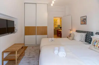a bedroom with two white beds and a television at Museum District Apartment in Athens