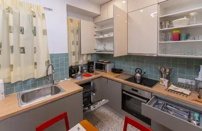 a kitchen with white cabinets and a sink at Museum District Apartment in Athens