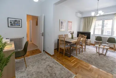 a dining room and living room with a table and chairs at Museum District Apartment in Athens