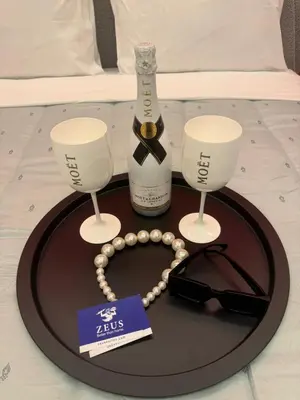 a tray with a bottle of wine and glasses on a bed at Artemis Patision Suite by Zeus Suites in Athens