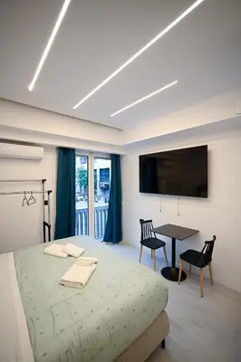 a bedroom with a bed and a table and a television at Erato Pedion Areos Suite by Zeus Suites in Athens