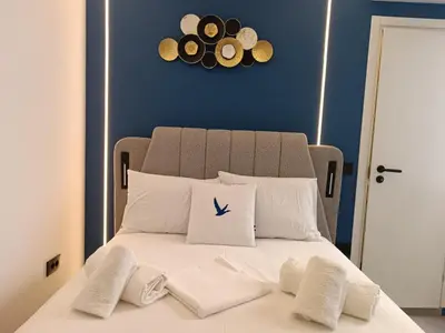 a bed with white pillows and a clock on the wall at Family Zeus elegant suite by Zeus suites in Athens