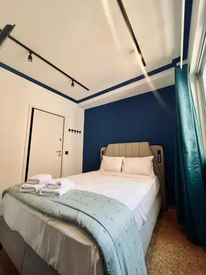 a bedroom with a bed with a blue wall at Family Ermou Suite by Zeus Suites in Athens