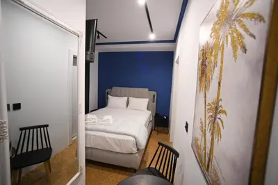a small bedroom with a bed and a palm tree at Family Ermou Suite by Zeus Suites in Athens