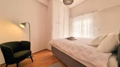 a bedroom with a bed and a chair and a window at Mata's Athenian Mosaic - super central city stay in Athens