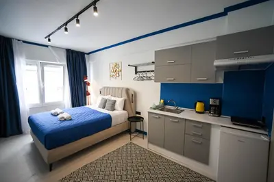 a blue and white bedroom with a bed and a kitchen at Plaka Voulis 45 by Zeus Suites in Athens