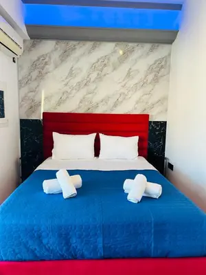 a bedroom with a blue bed with two pillows at Acropolis view family big veranda by Zeussuites in Athens