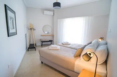 a white bedroom with a bed and a window at Mets-Athenian Horizon Escape in Athens