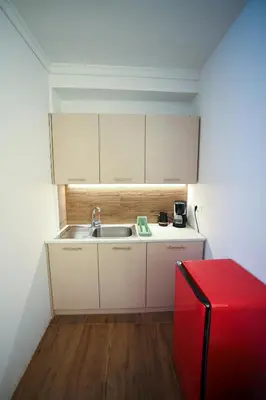 a small kitchen with a sink and a red refrigerator at Tsakalof 10 Kolonaki by Zeus Suites in Athens