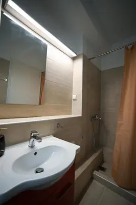 a bathroom with a sink and a mirror and a shower at Tsakalof 10 Kolonaki by Zeus Suites in Athens