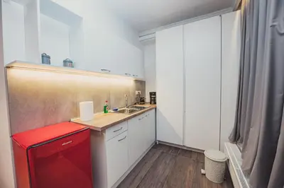a small kitchen with white cabinets and a red refrigerator at Tsakalof 10A Elegant Studio by Zeus Suites in Athens