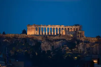 a building on top of a mountain at night at Acropolis Majestic View Residence Aiolou 97 by Zeussuites in Athens