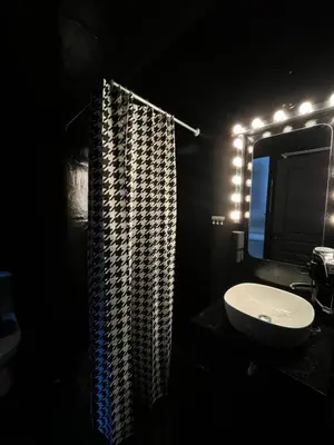 a dark bathroom with a sink and a shower at Tsakalof 17 Black in Athens