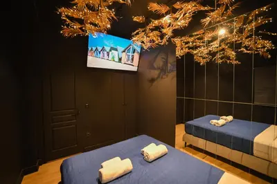 two beds in a room with a tv at Tsakalof 17 Black Suite by Zeus Suites in Athens