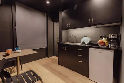 a kitchen with black cabinets and a table and a sink at Tsakalof 17 Black Suite by Zeus Suites in Athens