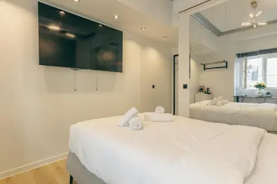 a white bedroom with two beds and a flat screen tv at Urban Diamond in Athens