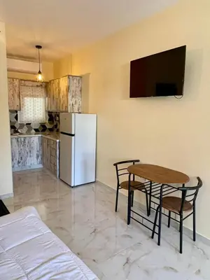 a kitchen with a table and a white refrigerator at Ivory Escape Apartment - ATH Airport in Spáta