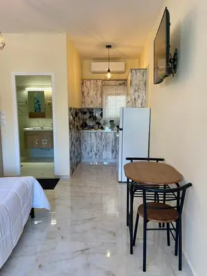 a room with a bed and a table and a kitchen at Ivory Escape Apartment - ATH Airport in Spáta