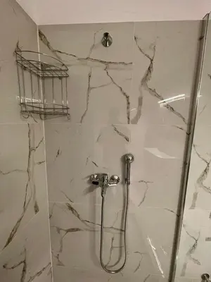 a shower in a bathroom with a marble wall at Ivory Escape Apartment - ATH Airport in Spáta