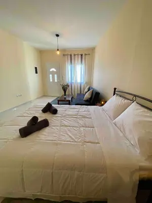 a large white bed with two brown towels on it at Ivory Escape Apartment - ATH Airport in Spáta