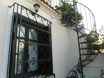 a wrought iron door with a spiral staircase next to a house at Nanny's Guest House in Plaka in Athens