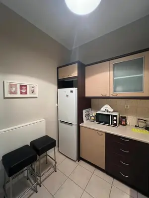a small kitchen with a refrigerator and two stools at Kolonaki hug in Athens