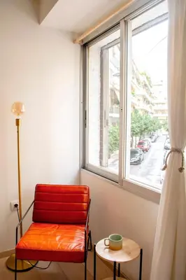a red chair sitting in front of a window at Studio in trendy Pagkrati district in Athens