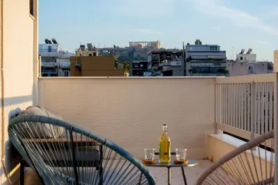 a table and chairs on a balcony with a bottle of wine at Studio with Acropolis View at Platia Avdi in Athens