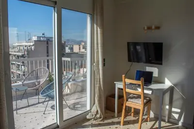 a room with a balcony with a desk and a television at Studio with Acropolis View at Platia Avdi in Athens