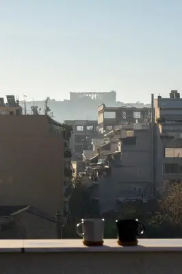 two coffee cups sitting on a ledge in a city at Studio with Acropolis View at Platia Avdi in Athens