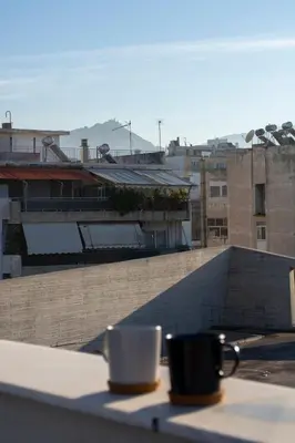two coffee cups sitting on a table on a balcony at Studio with Acropolis View at Platia Avdi in Athens
