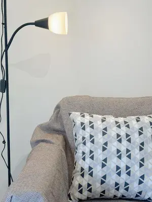 a lamp sitting next to a couch with a pillow at Palio Faliro Beach Luxury Apartments in Athens
