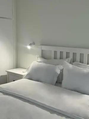 a white bedroom with two beds and a side table at Palio Faliro Beach Luxury Apartments in Athens