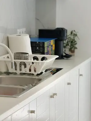 a kitchen counter with a dish drying rack next to a sink at Palio Faliro Beach Luxury Apartments in Athens