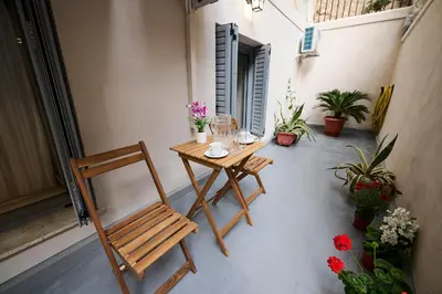 a table and a chair on a patio with flowers at Panos City Apartment - Private parking for motorcycles in Athens