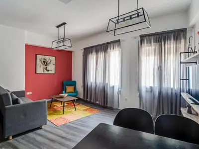 a living room with a red wall and a table and chairs at Central Hideaway Near Ermou Street Perfect For Groups And Families in Athens