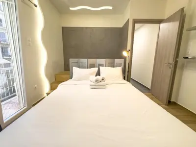 a large white bed in a room with a window at Athenian Hideaway - Spa Tub and Walk to Metro in Athens