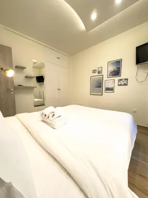 a white bed in a room with a tv at Athenian Hideaway - Spa Tub and Walk to Metro in Athens