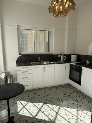 a kitchen with white cabinets and a chandelier at Graffiti One Studio in Athens