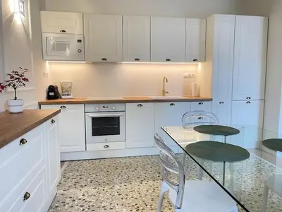 a kitchen with white cabinets and a glass table and chairs at White Gem of Piraeus in Piraeus